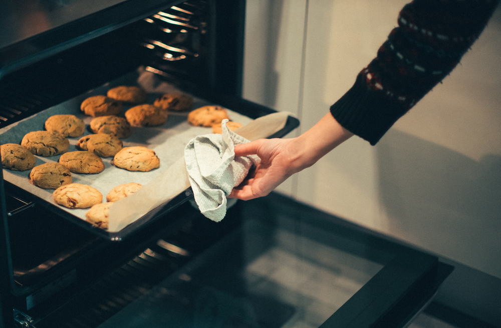 A woman takes chocolate chip cookies out of the oven