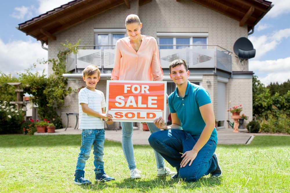 portrait-happy-young-family-sale-sign