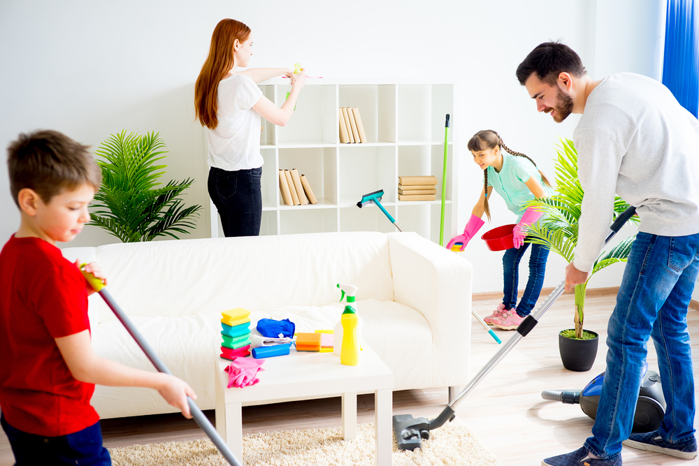 A family cleans up the living room, sweeping and dusting